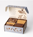 An open gift box of four slices of fudge with a decorative lid printed with the brand name 'Chocolate Moonshine' and botanical illustrations, photographed on a clean white background.