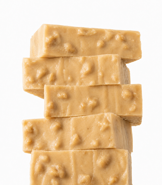 A stack of five slices of Maple Walnut Fudge with visible textured walnut pieces, isolated on a white background.