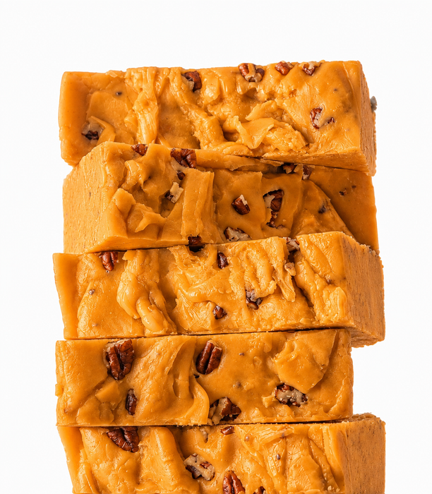 Five thick slices of pumpkin pecan pie fudge stacked vertically on a white background.